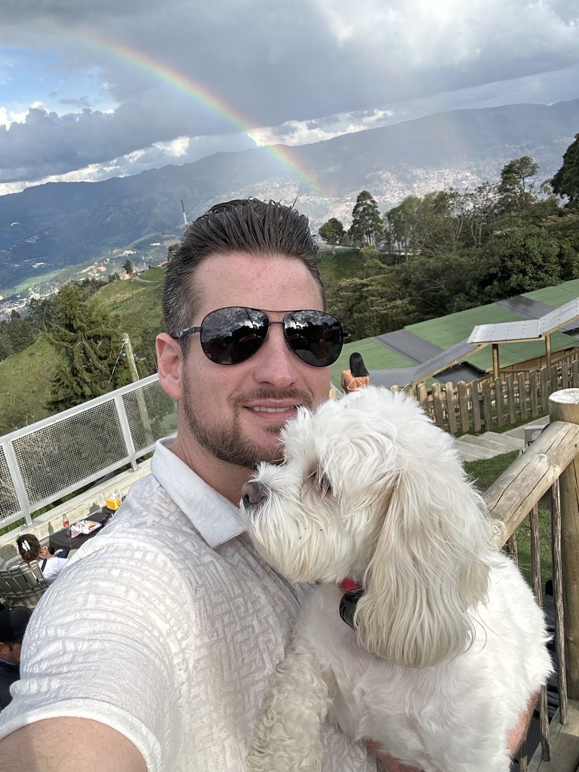 Adam holding Maya under a rainbow over the mountains
