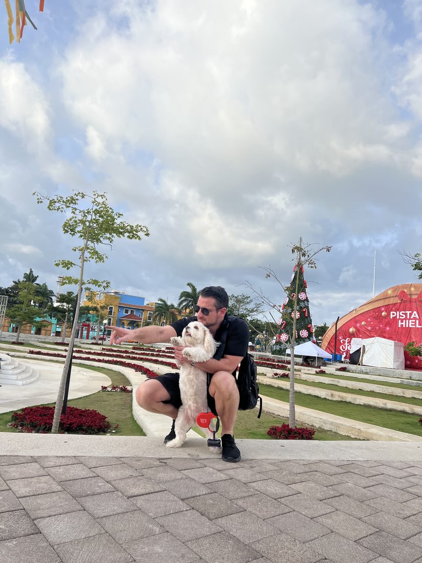 Adam and Maya in a plaza with a Christmas tree